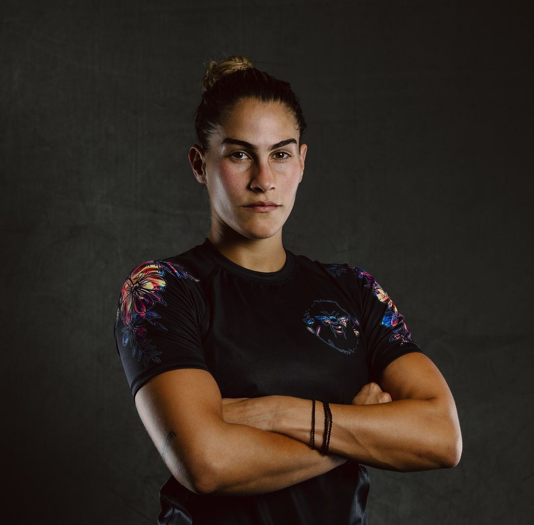 Fighter in a black floral Slay rashguard, arms crossed